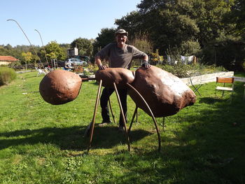 Portrait of smiling man standing by large ant on land