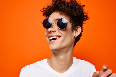 Portrait of smiling young man against orange background