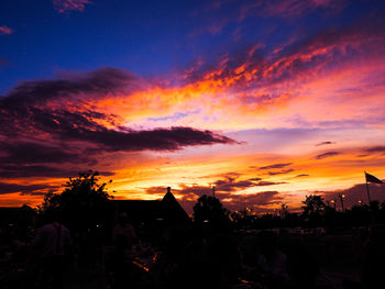Silhouette buildings in town against dramatic sky