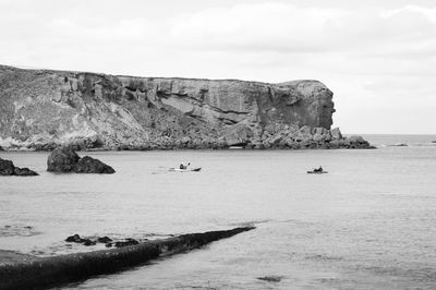 People fishing in sea against sky