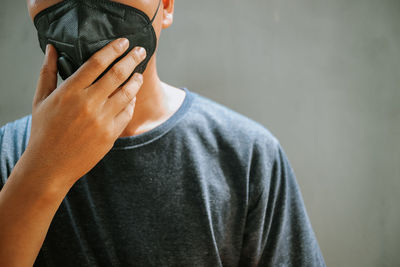 Midsection of mature man wearing pollution mask standing against wall