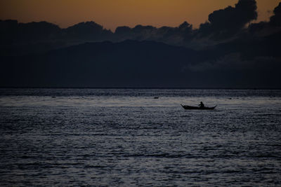 Silhouette birds on sea against sunset sky