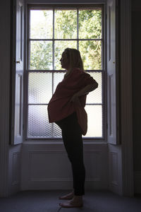 Woman standing by window at home
