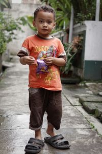 Full length portrait of cute boy standing on footpath