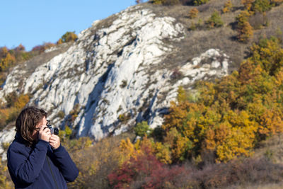 Full length of man standing on rock in autumn