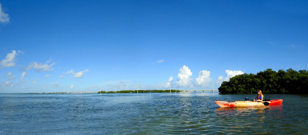 Young woman sitting on boat in sea against blue sky