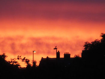 Low angle view of silhouette buildings against orange sky