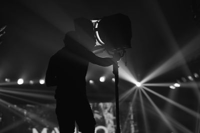 Rear view of silhouette man holding lighting equipment