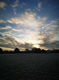 Scenic view of silhouette field against sky at sunset