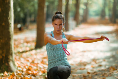 Woman exercising with elastic band outdoors in the fall, in public park