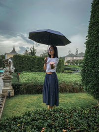 Rear view of woman with umbrella standing on field