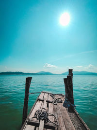 Wooden posts in sea against sky