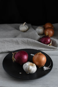 Close-up of onions and garlic in plate on table