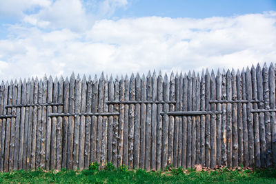 An old wooden fence made of sharp stakes in a russian siberian village