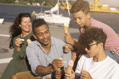 Family enjoying ice cream with each other while sitting on bench