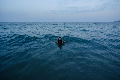 Woman standing in sea against sky