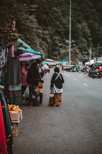 Rear view of people walking on road in city