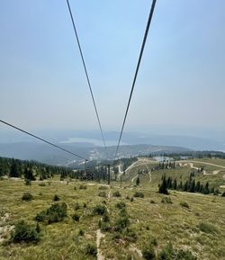 Overhead cable car on landscape against sky