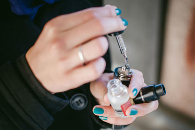 Close-up of woman holding electronic cigarette and dropper