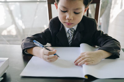 Boy writing in book on table