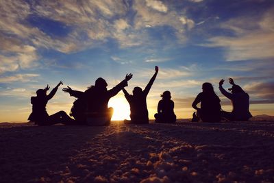 Silhouette people enjoying at beach against sky during sunset