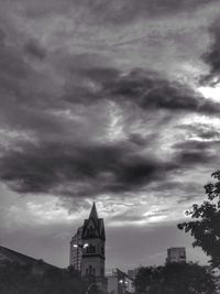 View of tower in city against cloudy sky