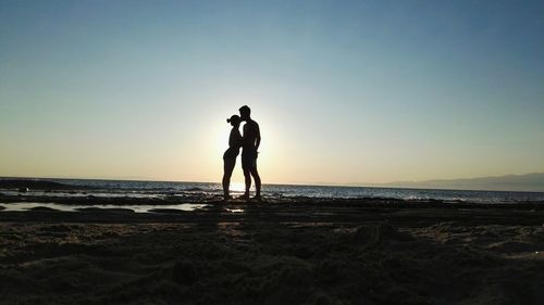 Silhouette couple kissing at beach against sky during sunset