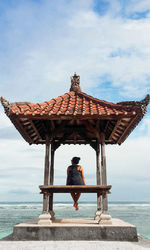 Man sitting at sea against sky