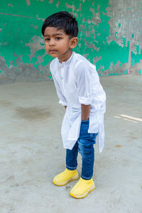 Full length of cute boy standing against wall