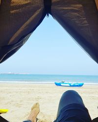 Low section of man on beach against clear sky