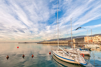 Boats moored in harbor against sky