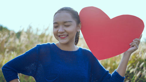 Young woman holding heart shape on land