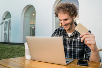 Young man using mobile phone while sitting on table