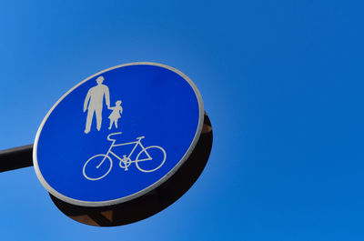 Low angle view of road sign against clear blue sky