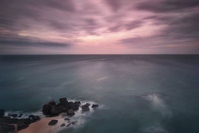 Scenic view of sea against dramatic sky during sunset