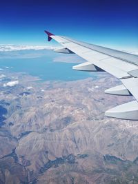 Aerial view of airplane flying over landscape against sky