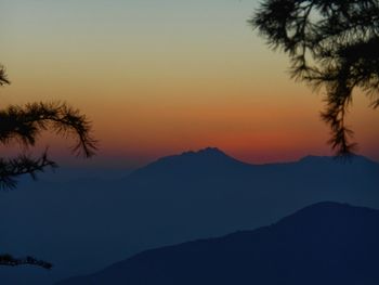 Scenic view of silhouette mountains against orange sky