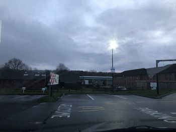 Road by buildings in city against sky