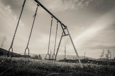 Empty swings at playground against sky