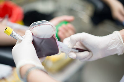 Cropped hands of doctor holding blood bag in hospital