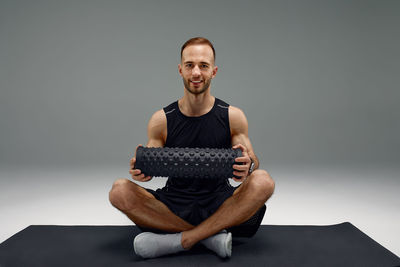 Portrait of young man exercising on sofa at home