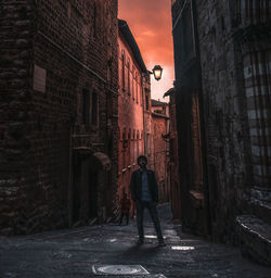 Rear view of woman walking on street amidst buildings