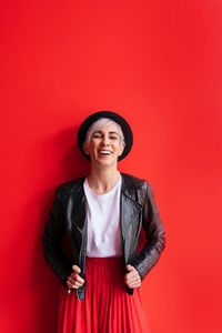 Smiling young woman standing against red background