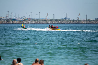 People in sea against clear sky