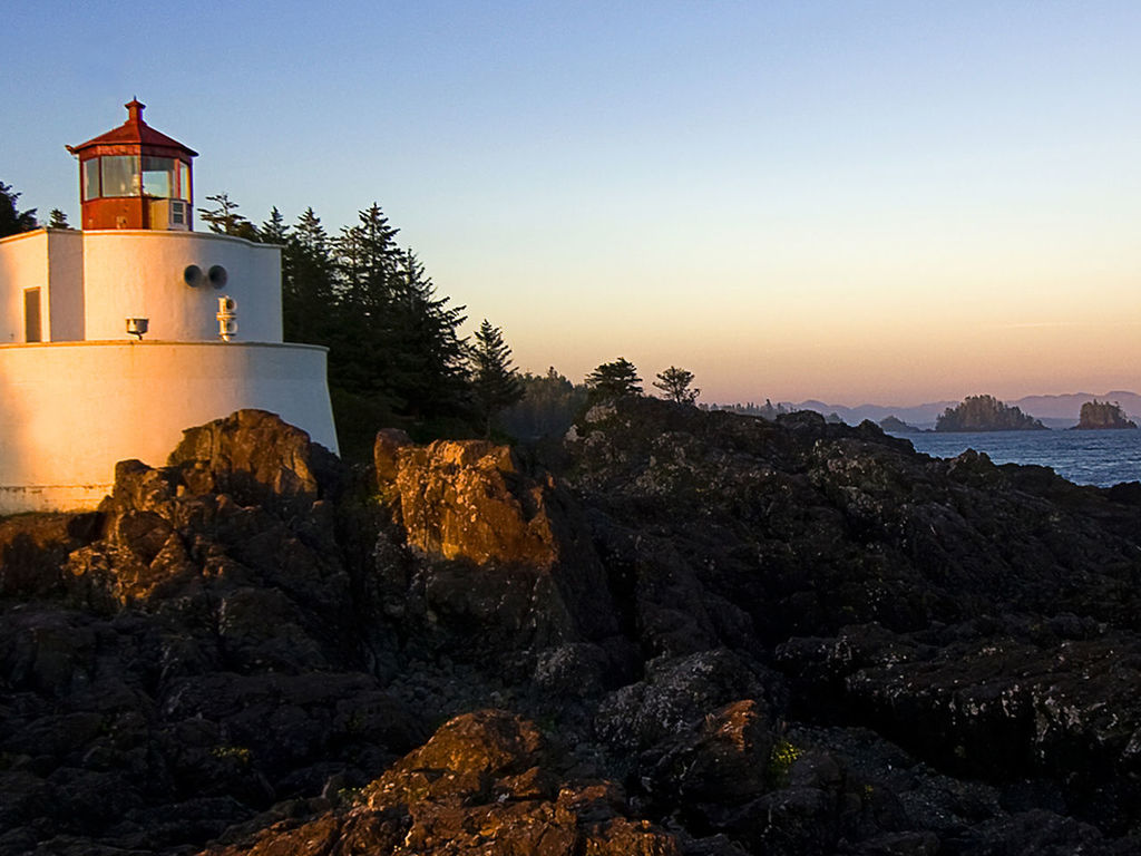 ROCKS BY SEA AGAINST BUILDINGS DURING SUNSET