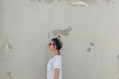 Side view of woman standing against wall