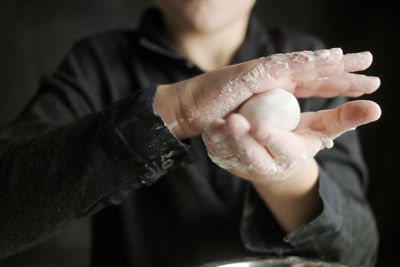 Midsection of man making dough in kitchen