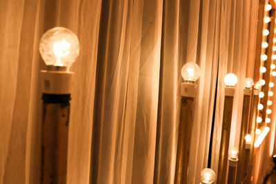Low angle view of illuminated light bulb hanging on ceiling