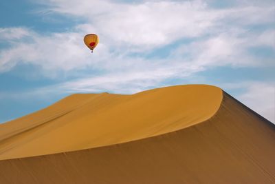 Low angle view of hot air balloons over desert against sky