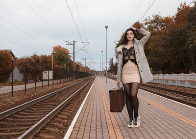 Full length portrait of young woman on railroad tracks
